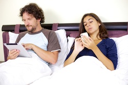 Couple working in bed with tablet and phone